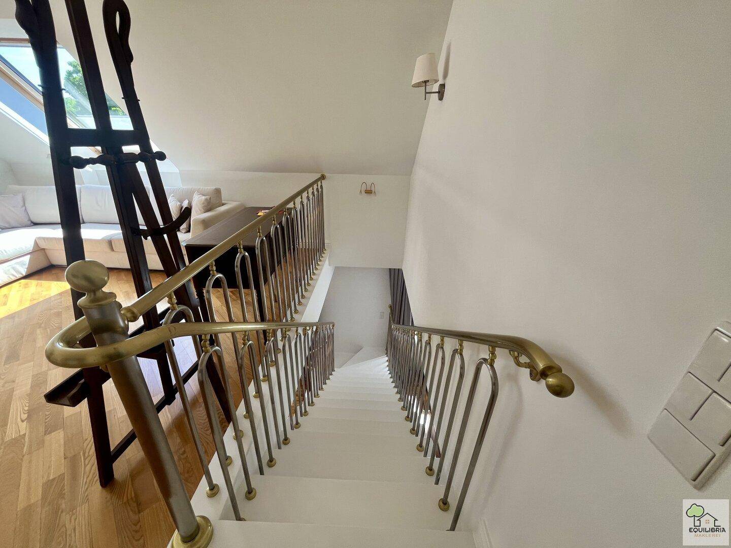 Elegante Treppe mit weiß gestrichenen Stufen und einem Messinggeländer.