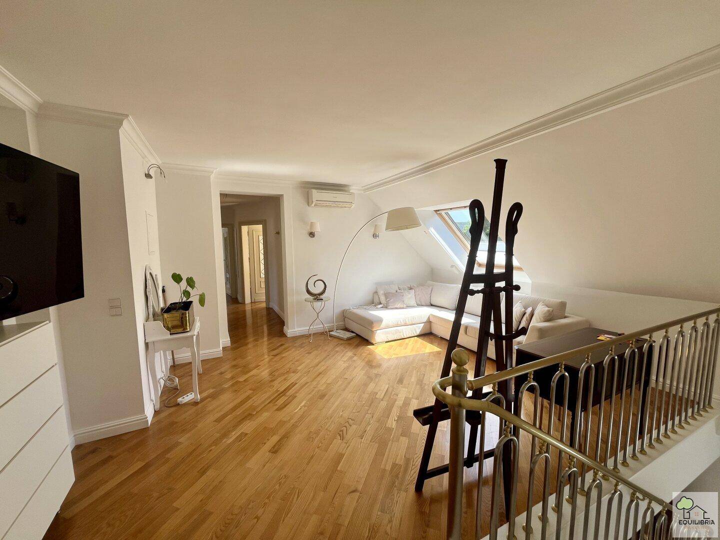 Geräumiger Wohnbereich mit Sofa, Holzfußboden, Dachfenster und Klimaanlage.