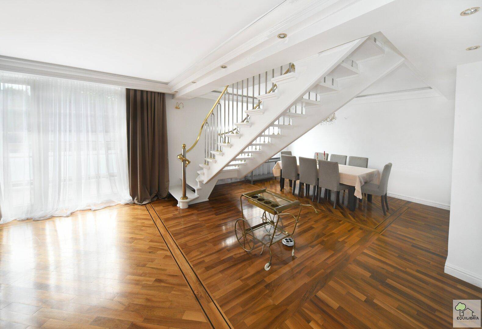 Offener Wohn- und Essbereich mit elegantem Parkettboden und einer stilvollen Treppe.