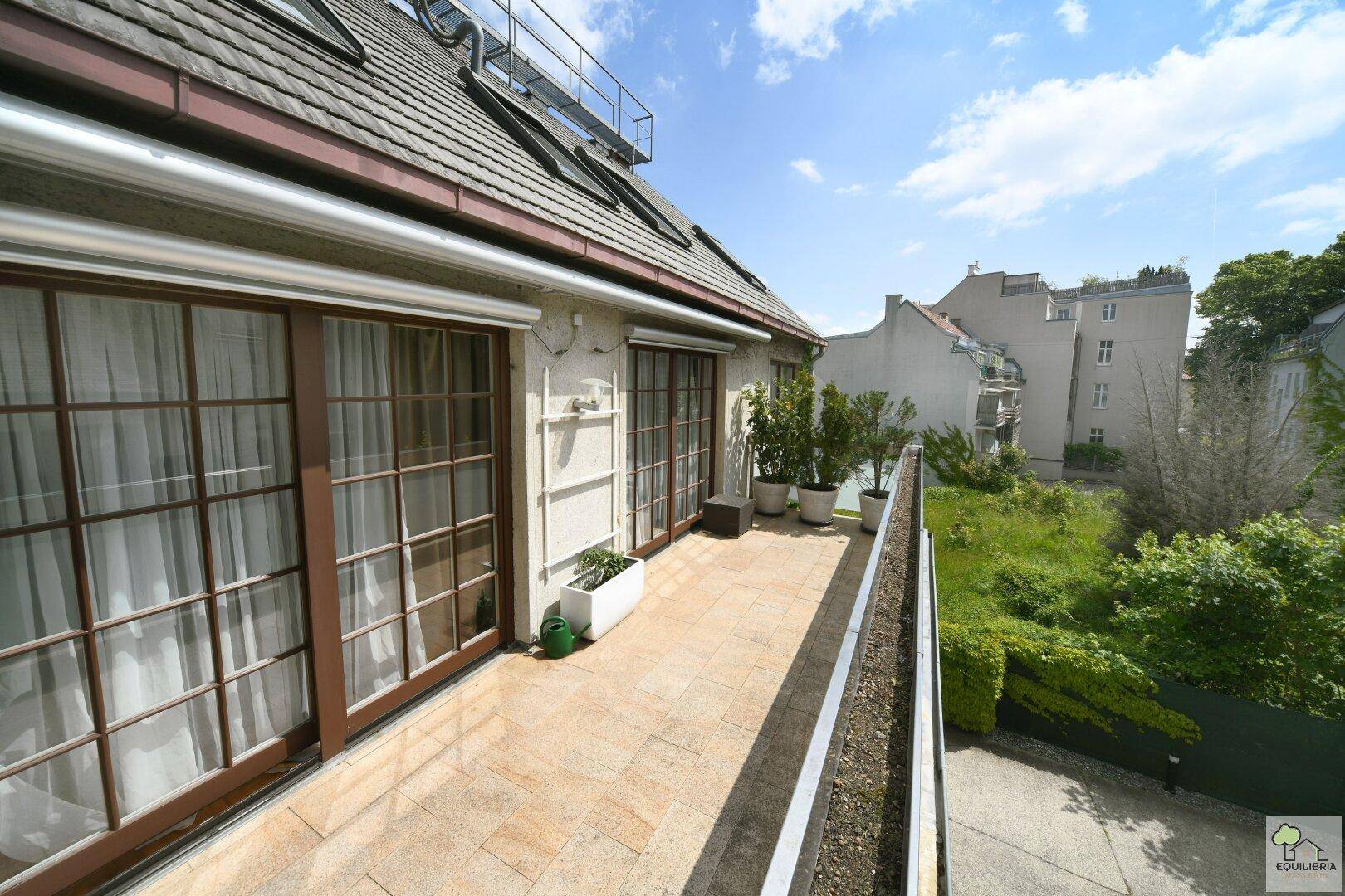 Geräumiger Balkon mit Fliesenboden, Pflanzen und Blick auf die Umgebung.
