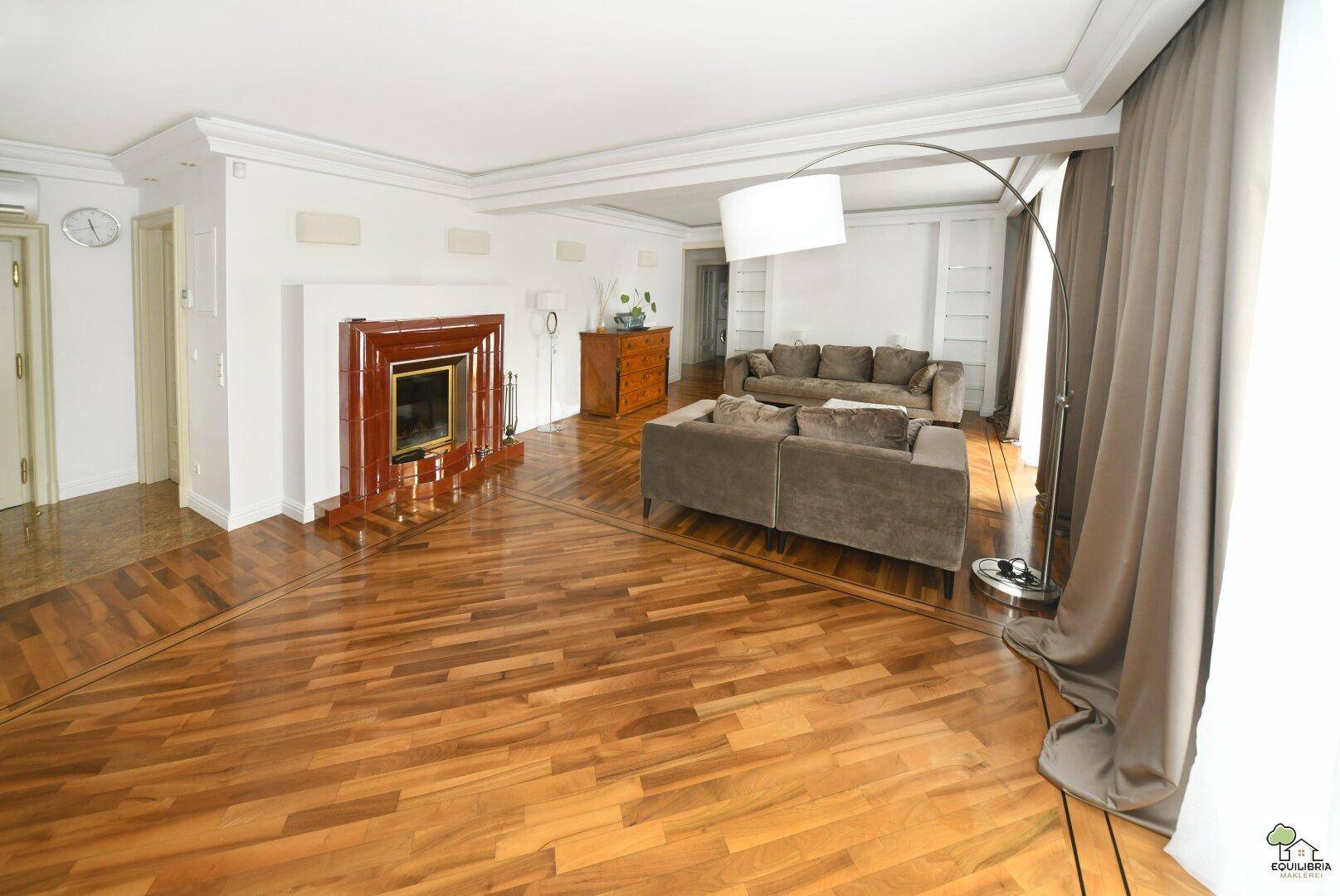 Geräumiges Wohnzimmer mit elegantem Parkettboden, einem dekorativen Kamin und bequemen Sofas.
