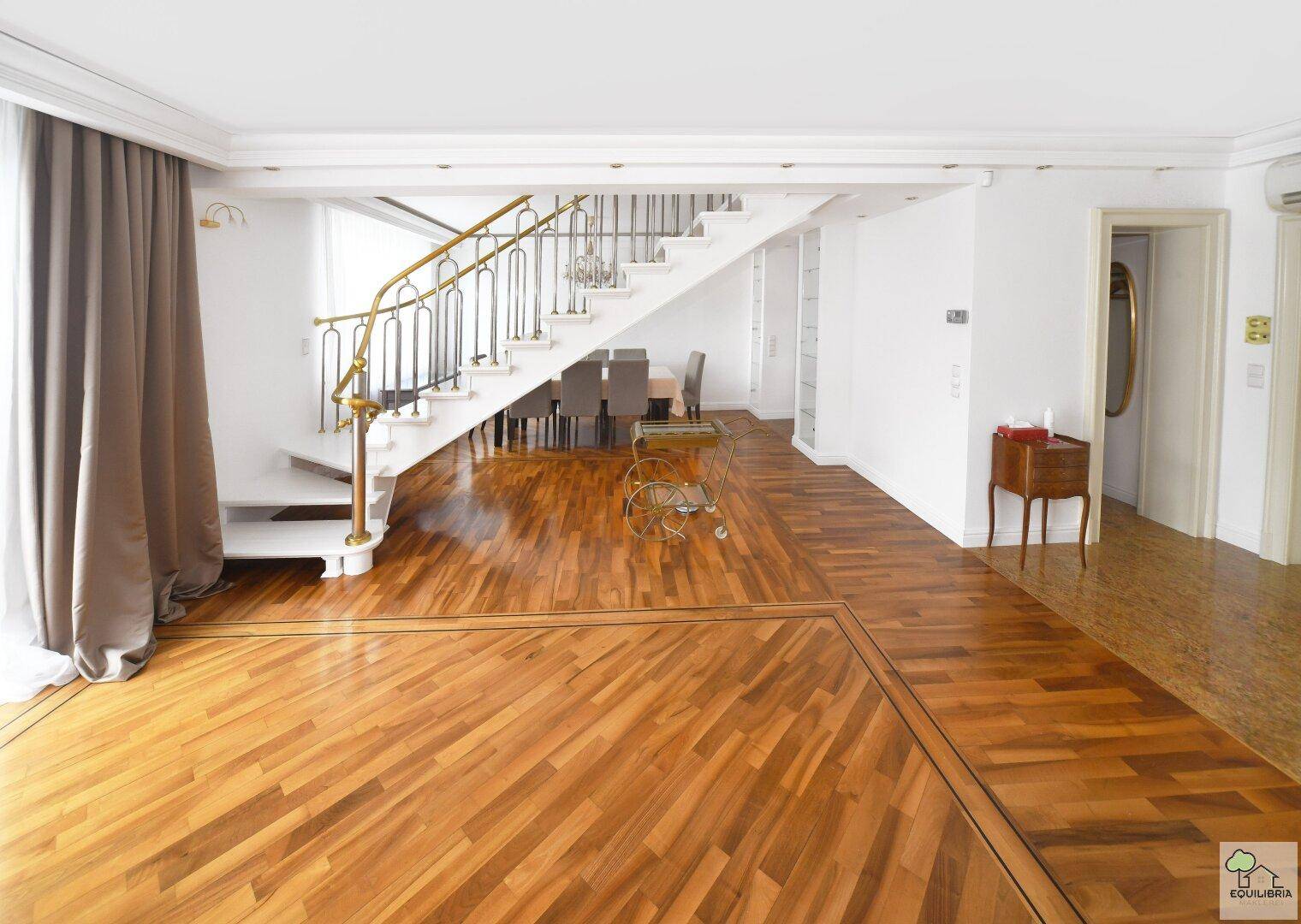 Offener Wohn- und Essbereich mit eleganter Treppe, Parkettboden und viel Tageslicht.