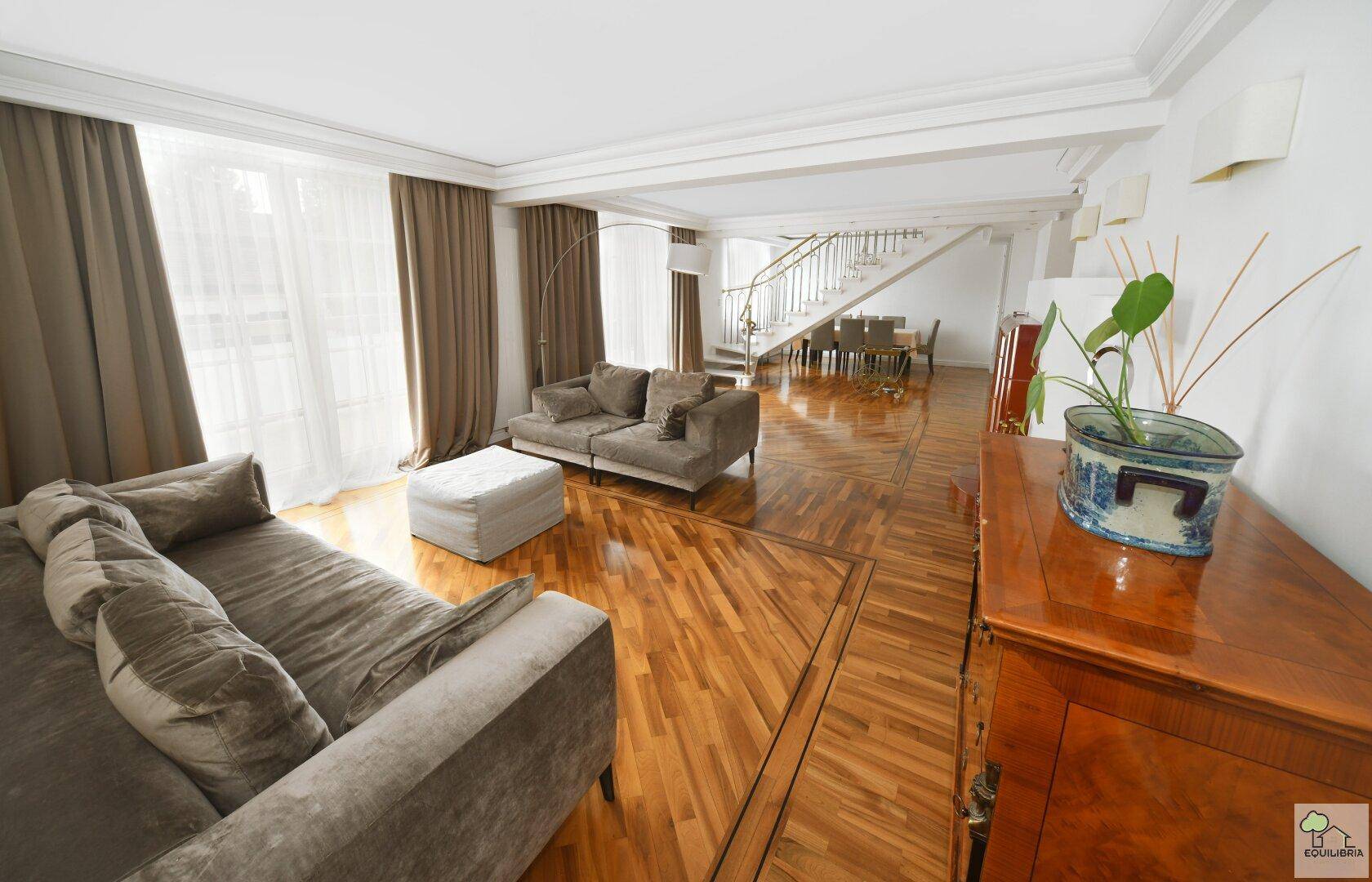 Heller Wohn- und Essbereich mit Parkettboden, bequemen Sofas und einem antiken Sideboard.