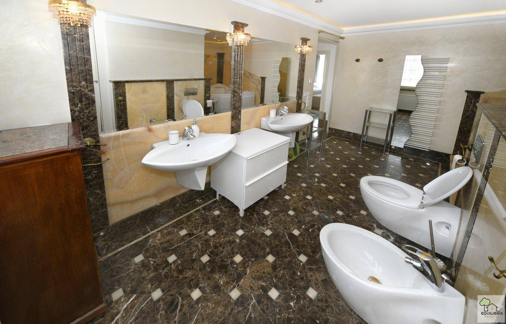 Elegantes Badezimmer mit dunklem Marmorboden, zwei Waschbecken und einem großen Spiegel.