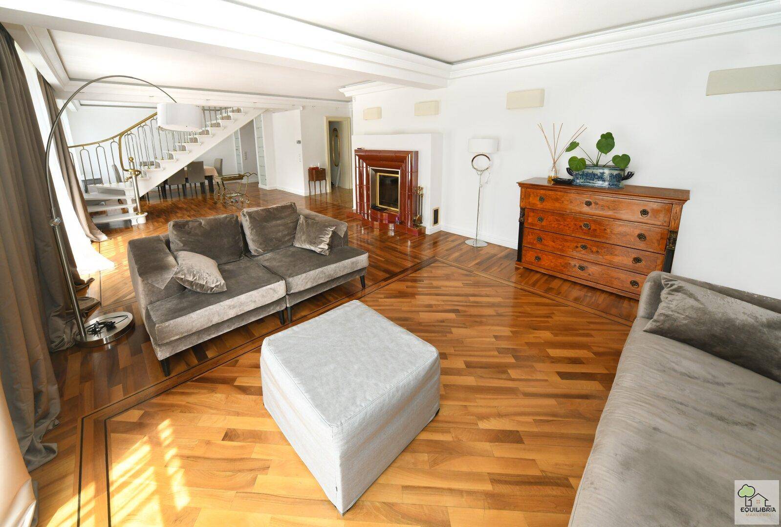 Helles Wohnzimmer mit Parkettboden, bequemen Sofas und einem dekorativen Kamin.
