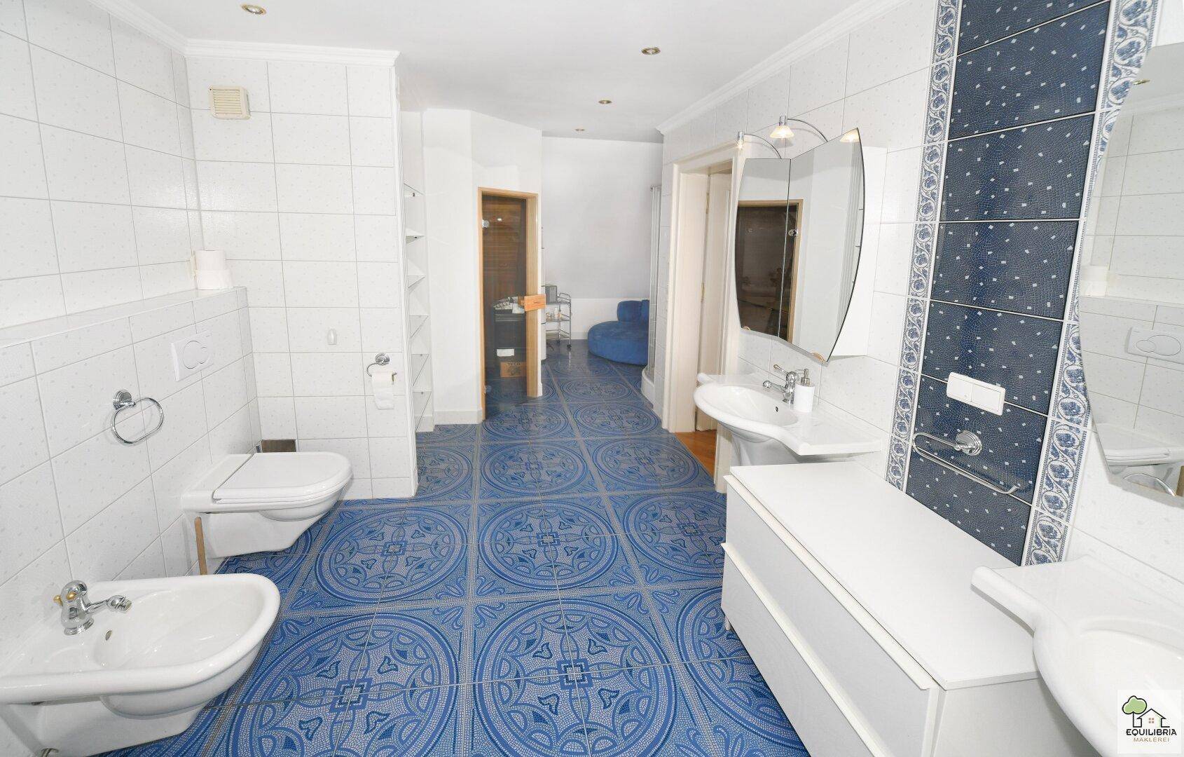 Helles Badezimmer im Dachgeschoss mit blauen Fliesen, Doppelwaschbecken und großem Spiegel.