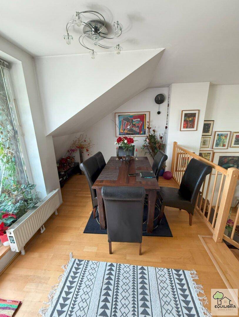 Heller Essbereich mit Holztisch, Lederstühlen und Dachschräge, angrenzend an ein Fenster.
