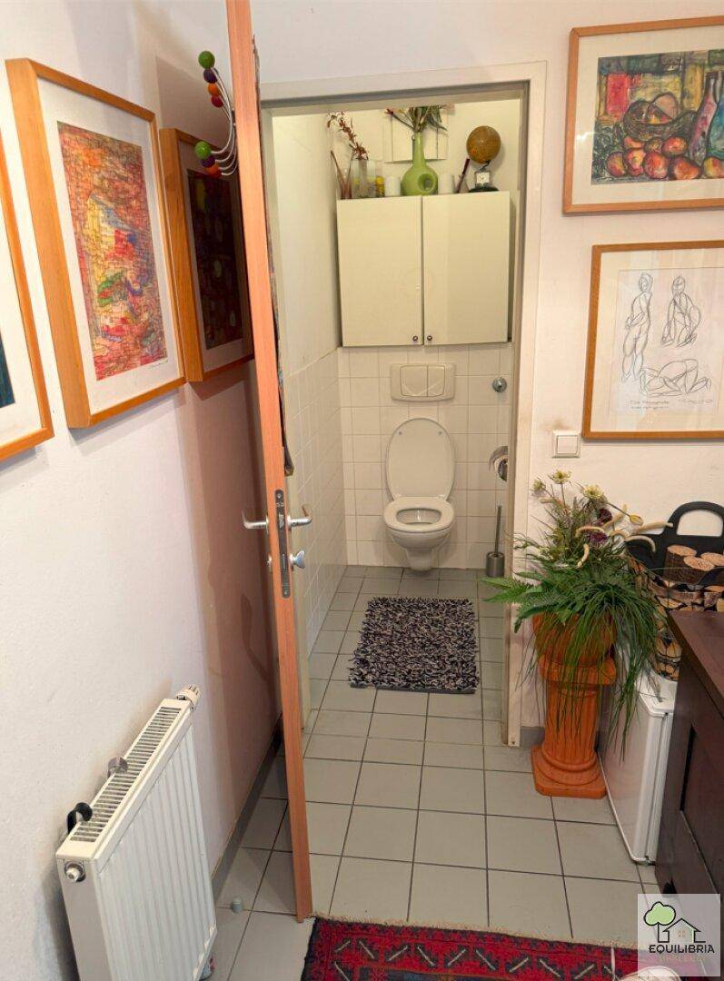 Helles Gäste-WC mit weißen Fliesen, Wand-WC und kleinem Waschbecken.