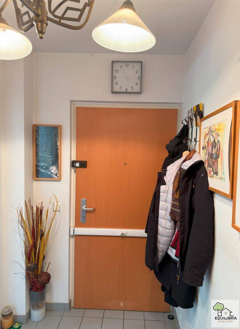 Eingangsbereich mit Holztür, Garderobe und Fliesenboden.