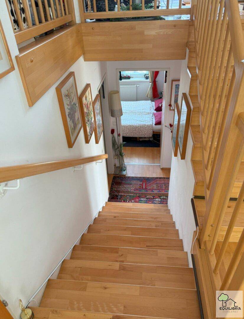 Holztreppe führt hinunter zu einem Schlafzimmer, umgeben von Kunstwerken.