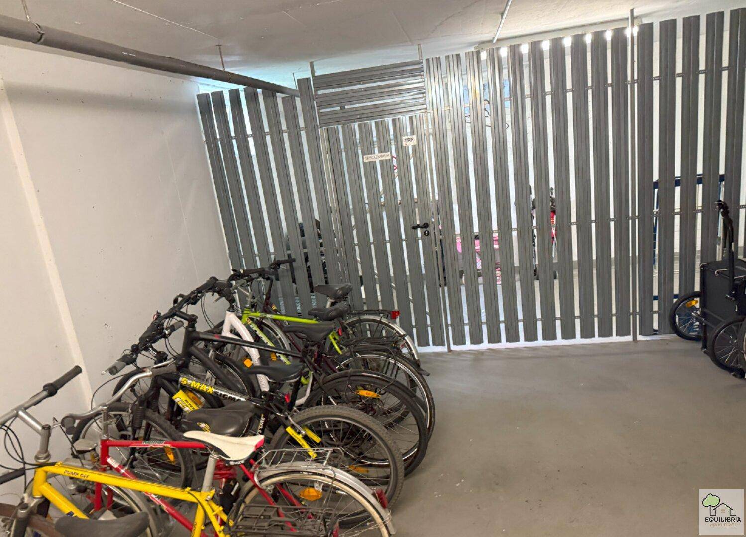Fahrradraum im Untergeschoss mit zahlreichen Fahrrädern und Metallabtrennungen.
