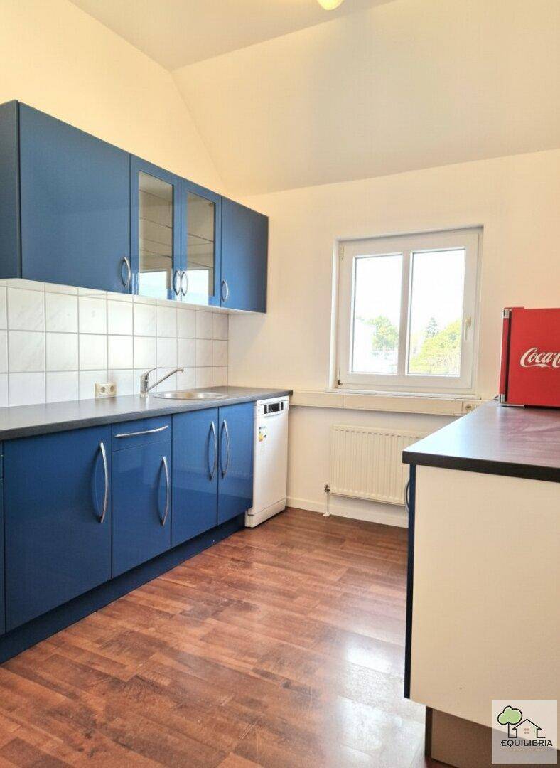Funktionale Küche mit blauen Schränken, weiß gefliestem Spritzschutz und einem Fenster.