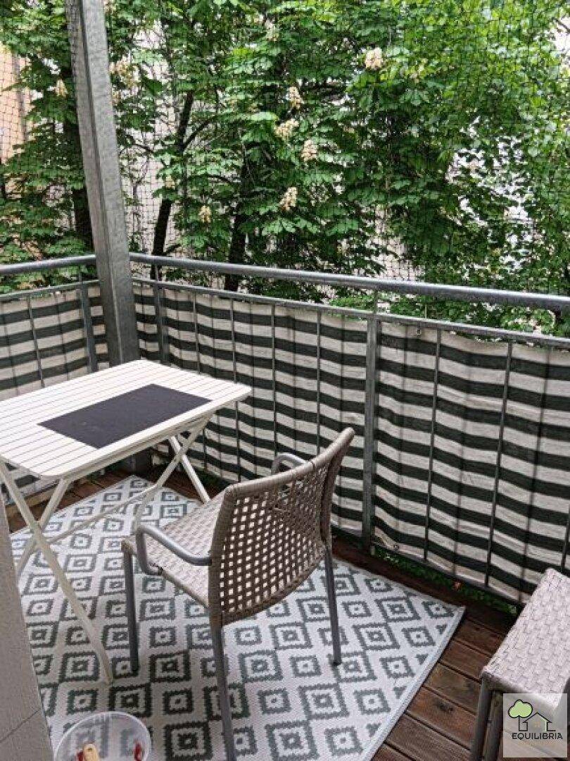 Gemütlicher Balkon mit Sitzgelegenheiten, Teppich und einem angenehmen Blick ins Grüne.