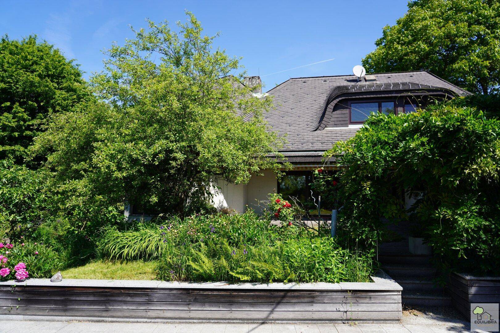 Gepflegter Vorgarten mit üppiger Bepflanzung und Blick auf die charmante Hausfassade.