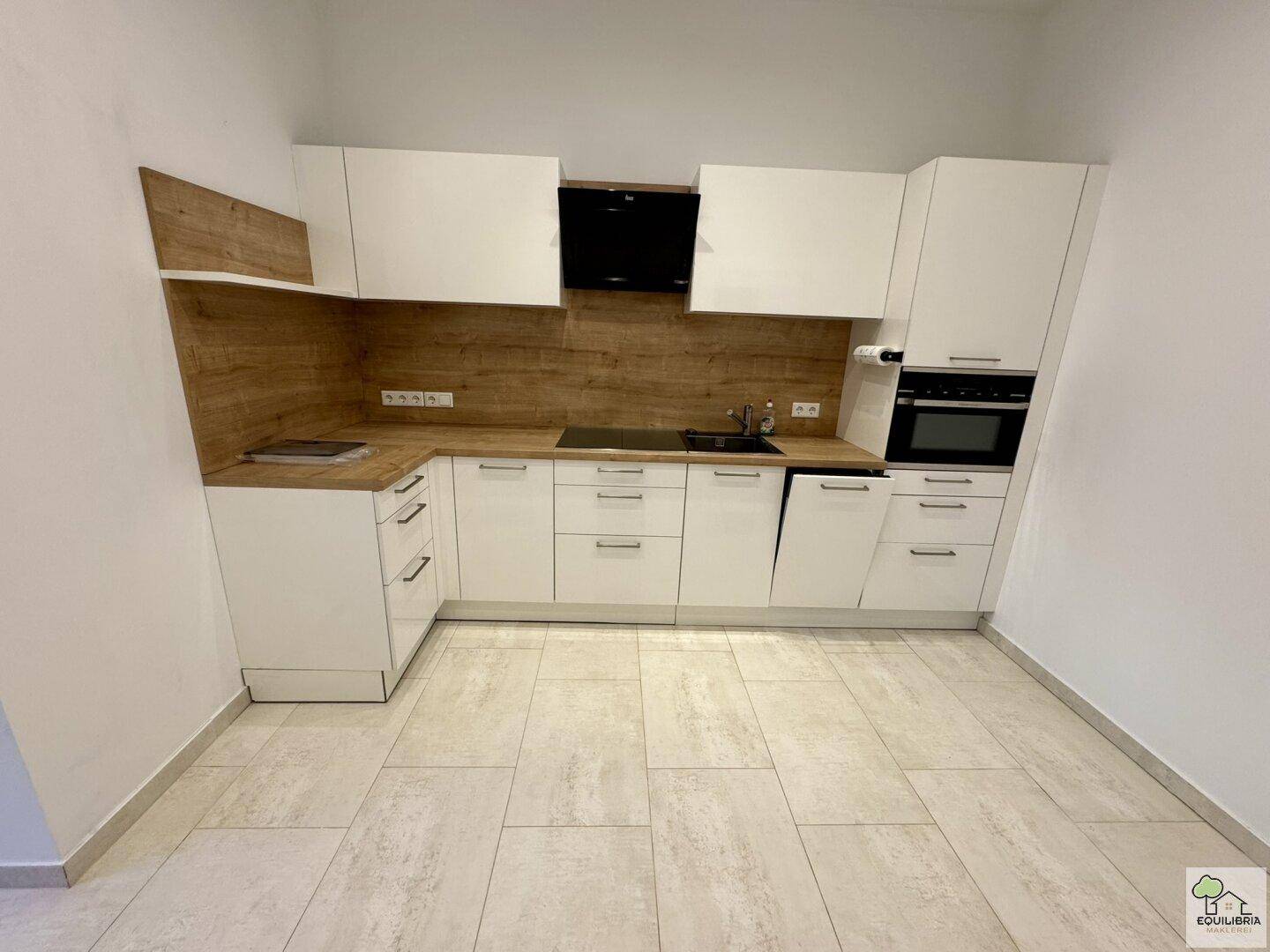 Moderne Einbauküche mit weißen Hochglanzfronten, Holzakzenten und integrierten Küchengeräten.