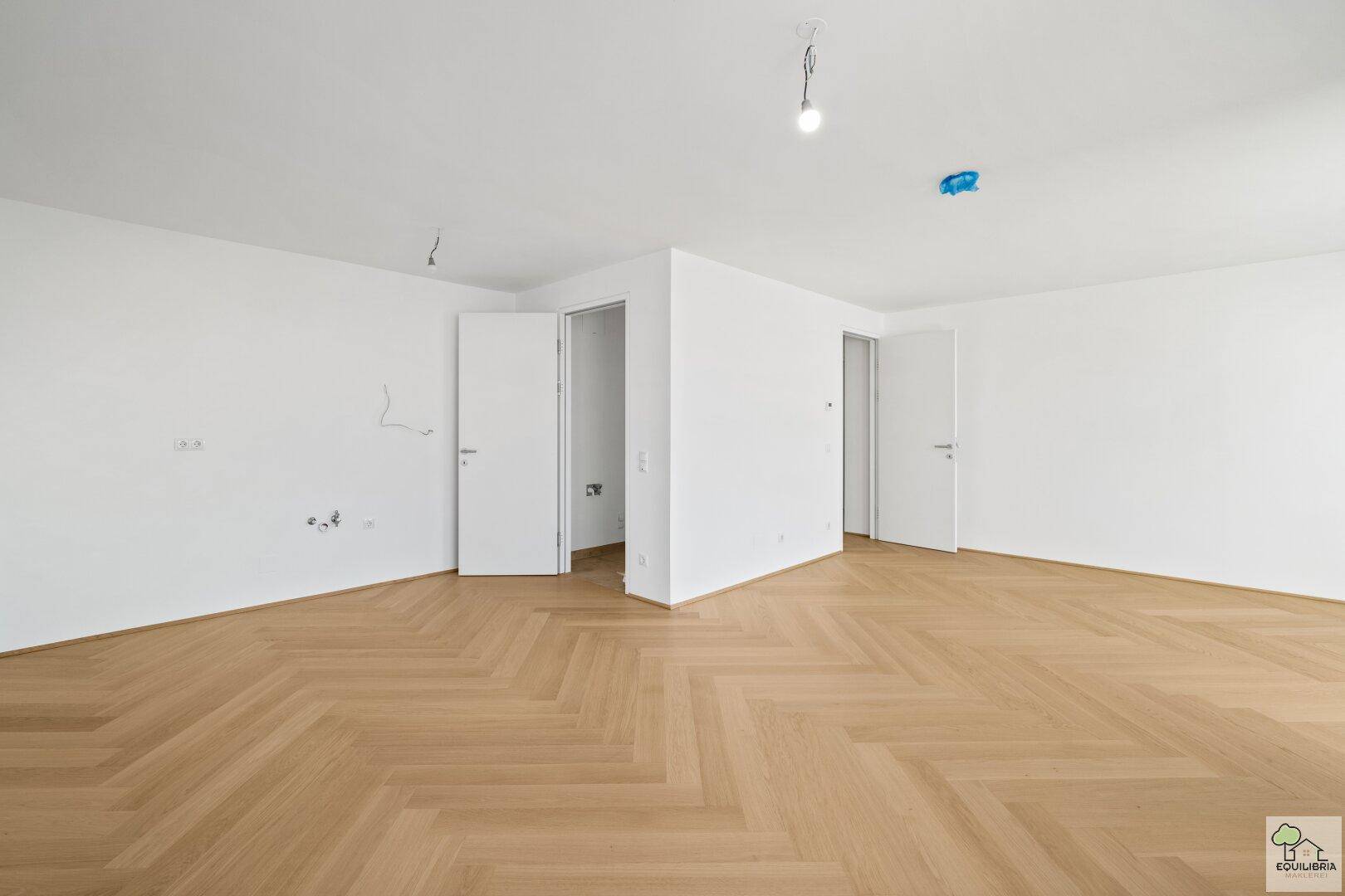 Geräumiger, heller Raum mit Fischgrätparkett und weißen Wänden, bereit zur individuellen Gestaltung.