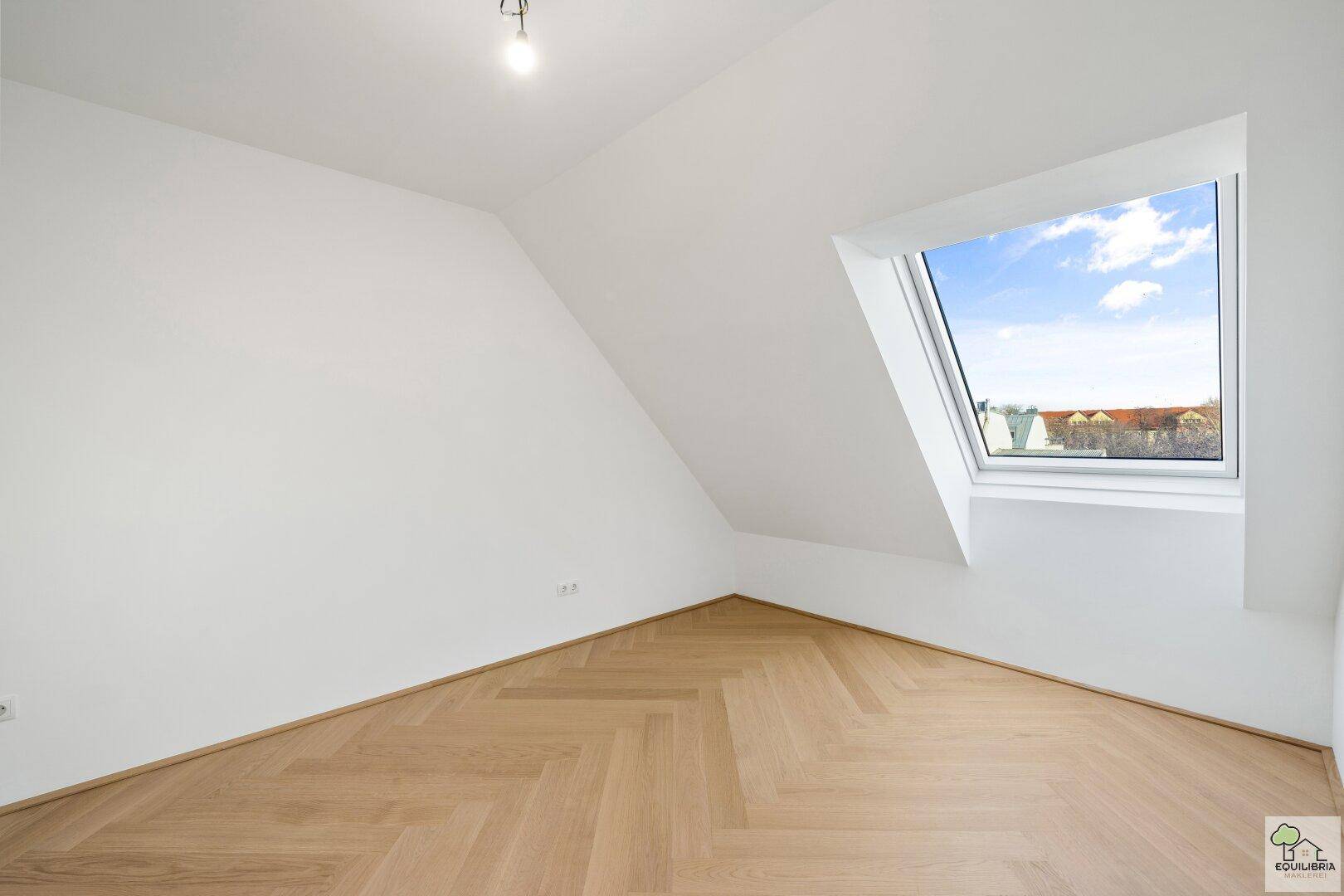 Lichtdurchflutetes Zimmer mit Dachschräge, Dachfenster und hochwertigem Fischgrätparkett.