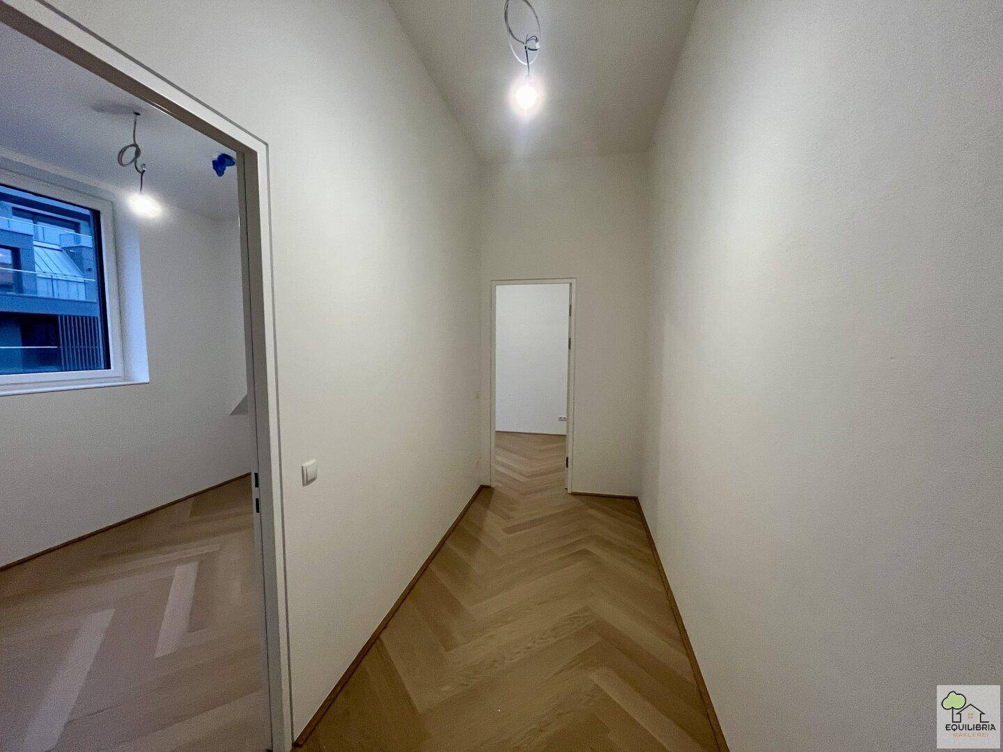 Heller Flur mit Fischgrätparkettboden, der zu weiteren Zimmern im Dachgeschoss führt.