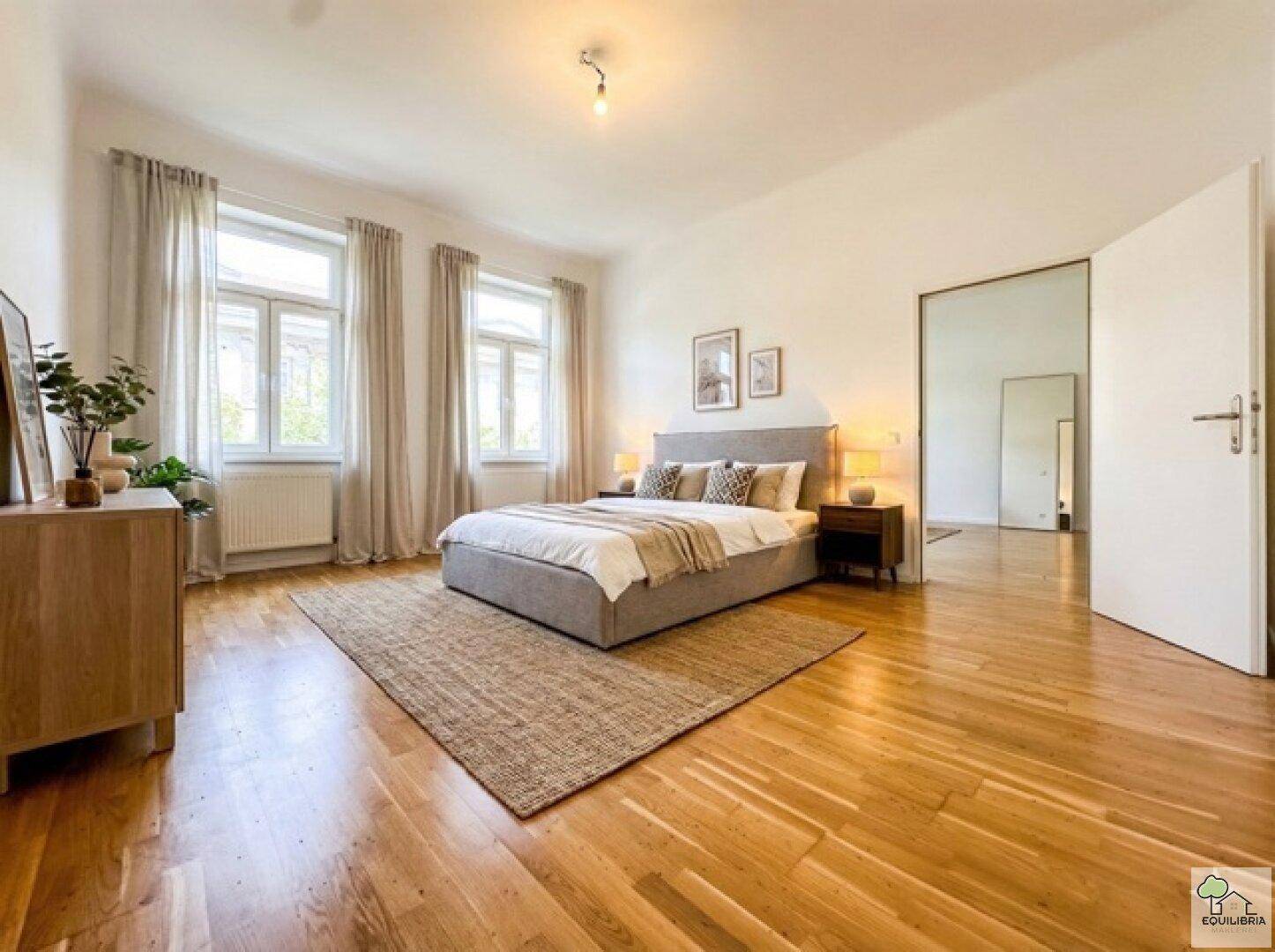 Geräumiges Schlafzimmer mit Holzboden, großen Fenstern und einem bequemen Doppelbett.