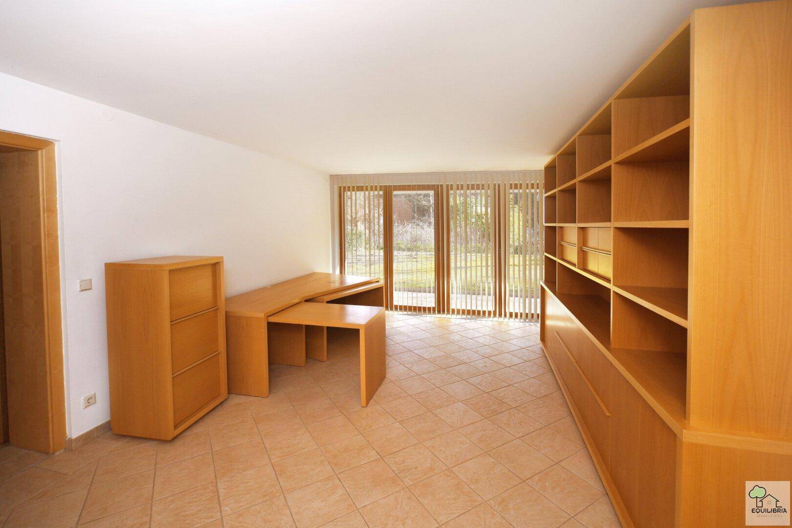 Geräumiges Büro mit Holzregalen, Schreibtisch und Zugang zum Garten durch große Fenster.
