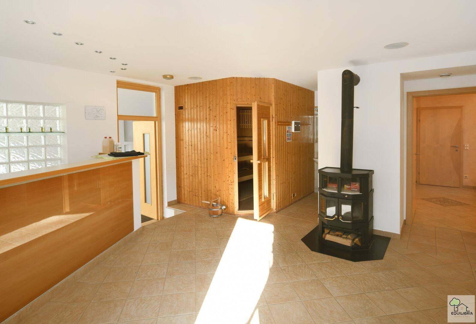 Wellnessbereich mit Holzsauna, Kaminofen und gefliestem Boden, ideal zur Entspannung.