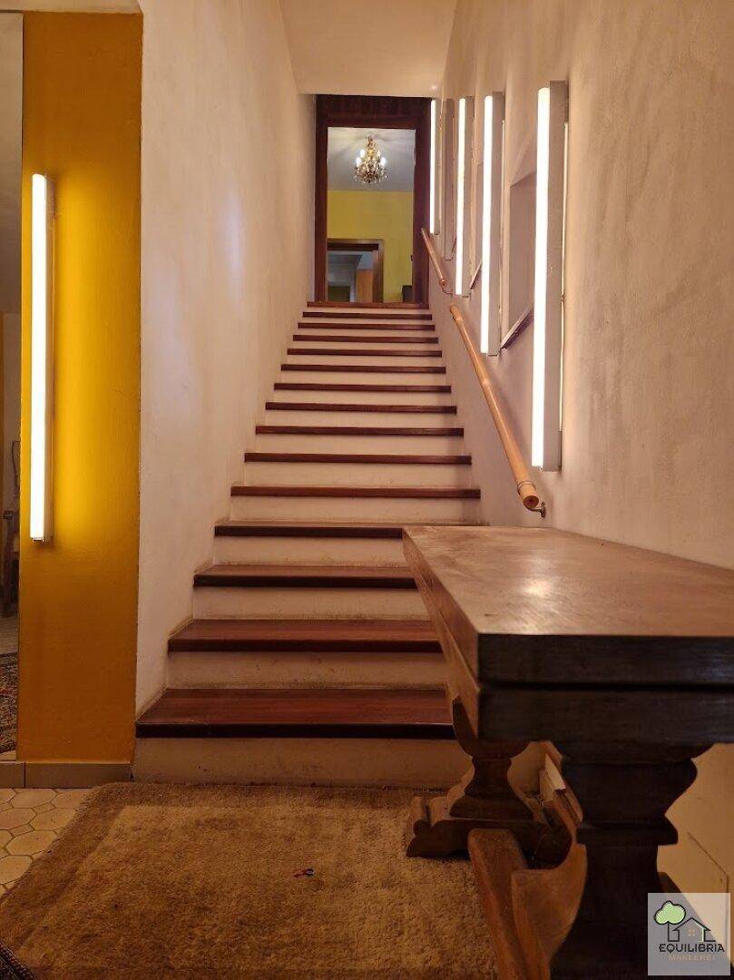 Heller Treppenaufgang mit Holzstufen und moderner Wandbeleuchtung, die nach oben führt.