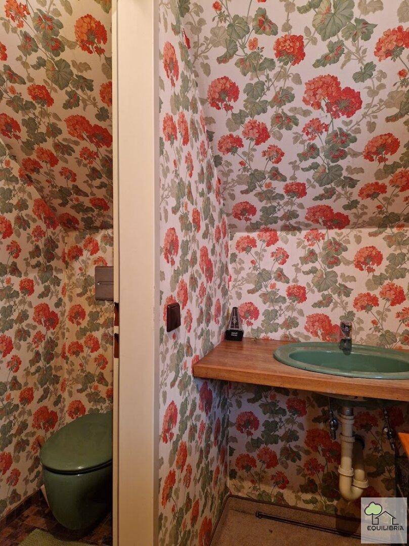 Charmantes Gäste-WC mit floraler Tapete, grünem Waschbecken und passender Toilette.
