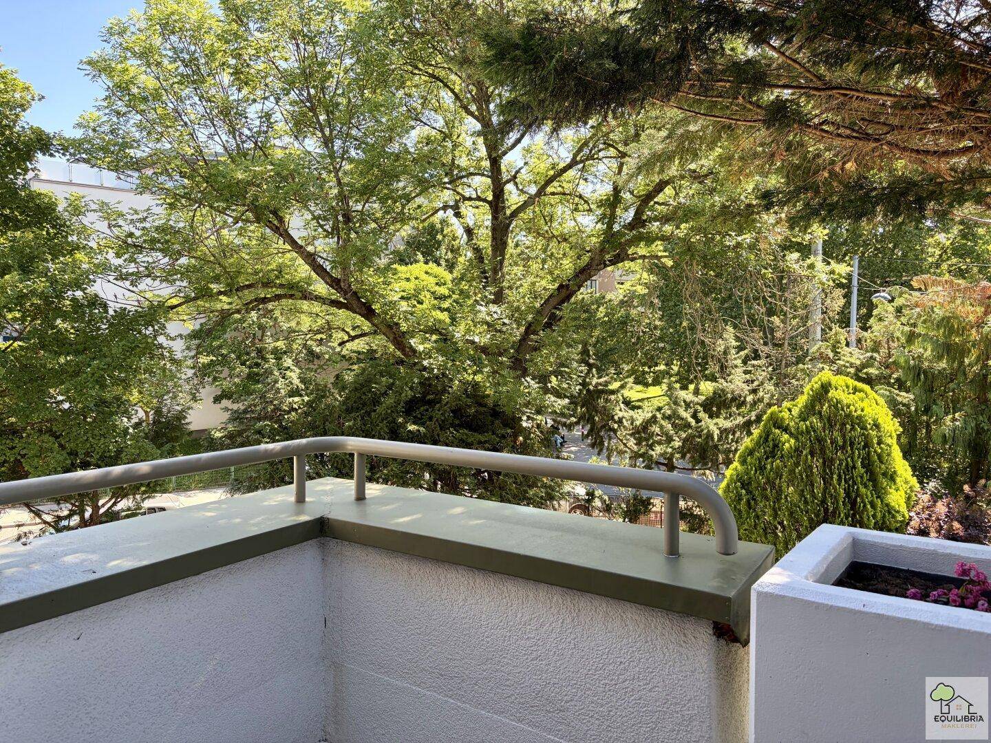 Balkon mit Blick ins Grüne, umgeben von Bäumen und Sträuchern, ideal zur Entspannung.