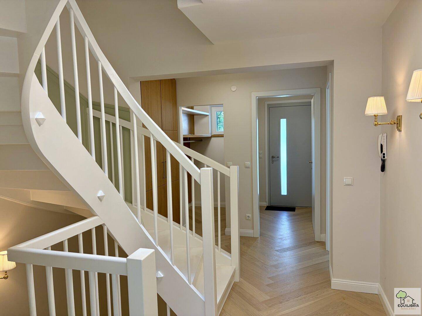 Eingangsbereich mit eleganter Treppe und Zugang zu einem begehbaren Kleiderschrank.