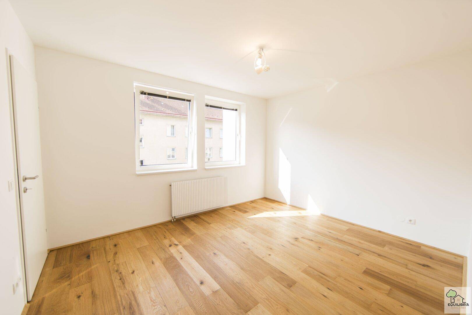 Helles Schlafzimmer mit Holzboden und großen Fenstern, bietet viel Tageslicht.