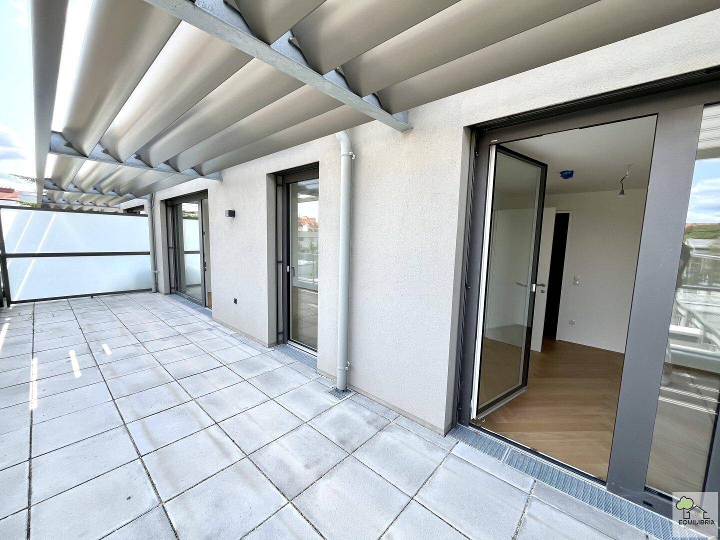 Geräumige Terrasse mit Fliesenboden und direktem Zugang zu den hellen Innenräumen.