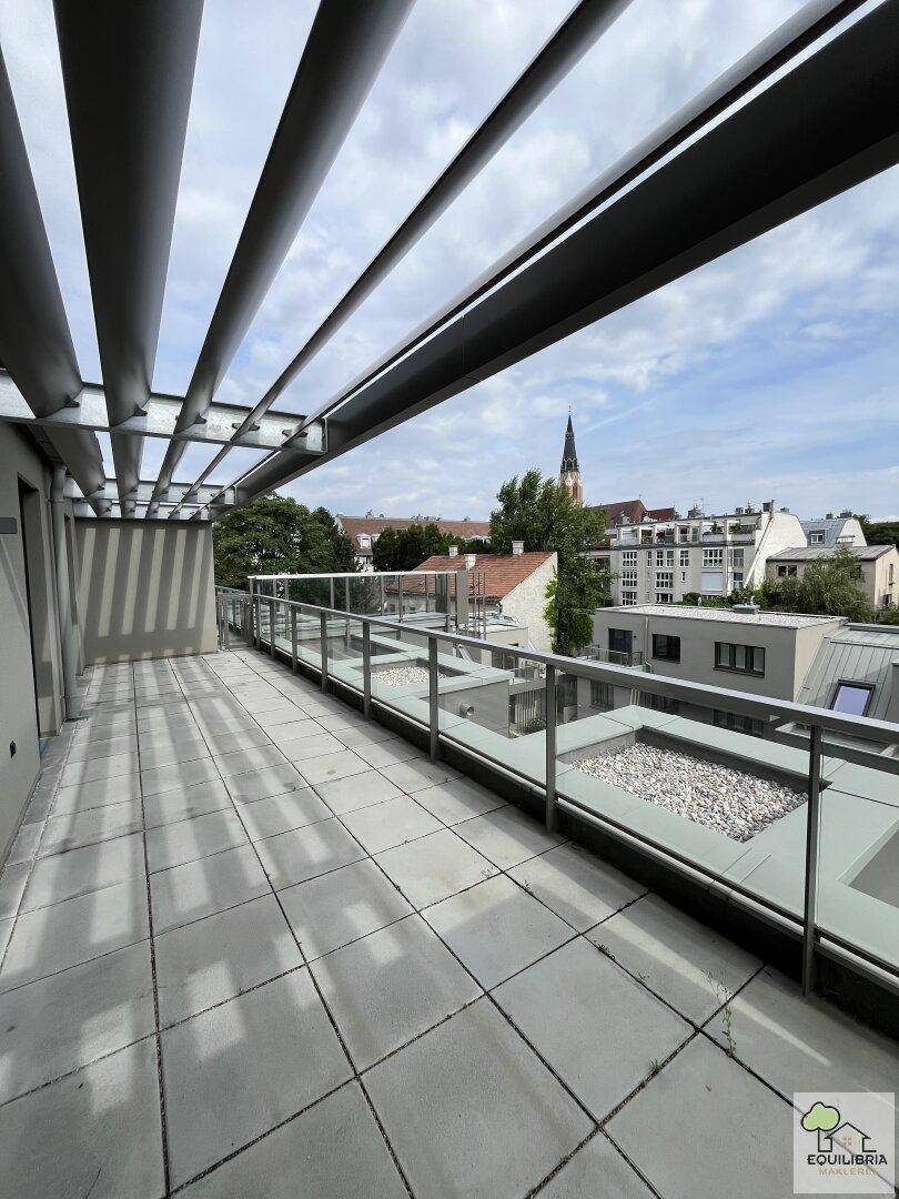 Moderne Dachterrasse mit Pergola, Fliesenboden und weitem Blick über die Stadt.