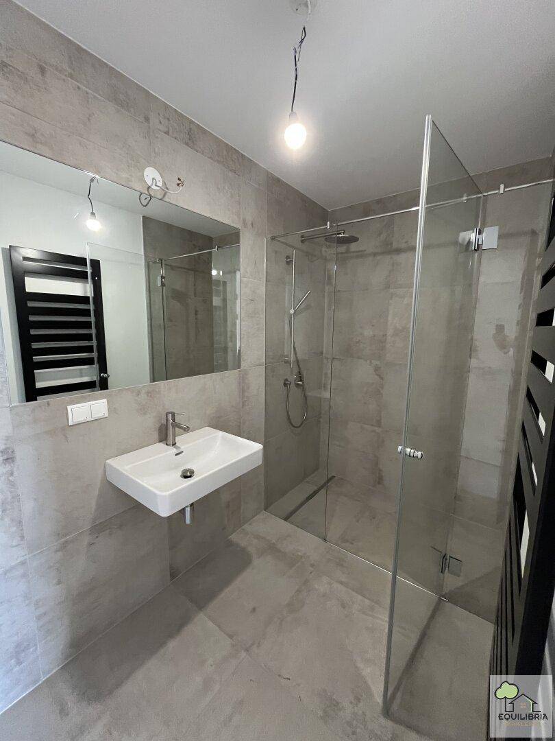 Modernes Badezimmer mit ebenerdiger Dusche, Waschbecken und beheiztem Handtuchhalter.