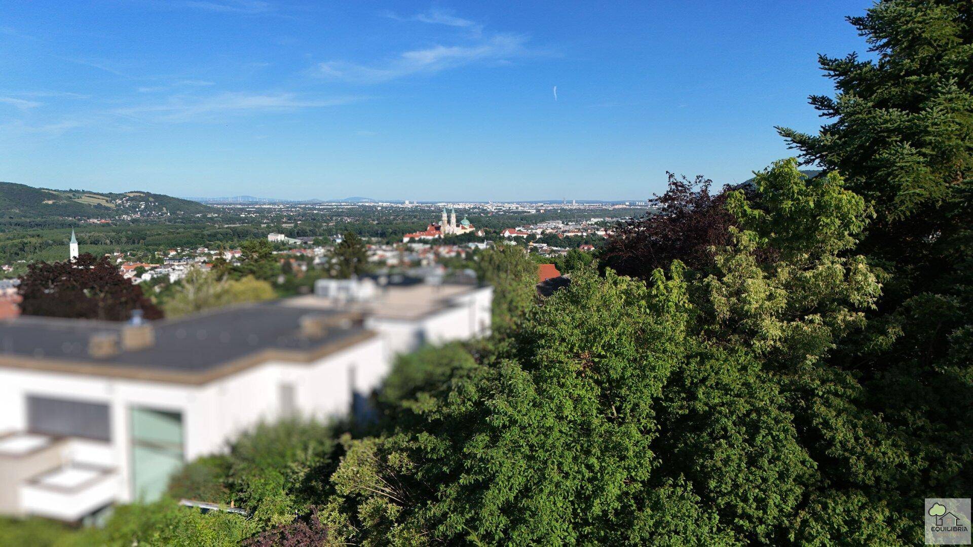 Weitläufiger Blick über die Stadt und umliegende Hügel mit markanter Kirche im Zentrum.