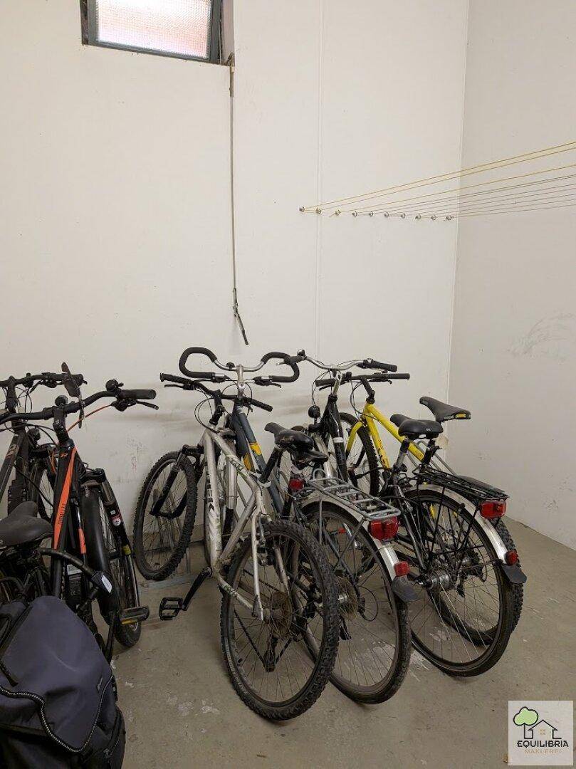Gemeinschaftlicher Fahrradraum mit mehreren Fahrrädern und Wäscheleinen an der Wand.