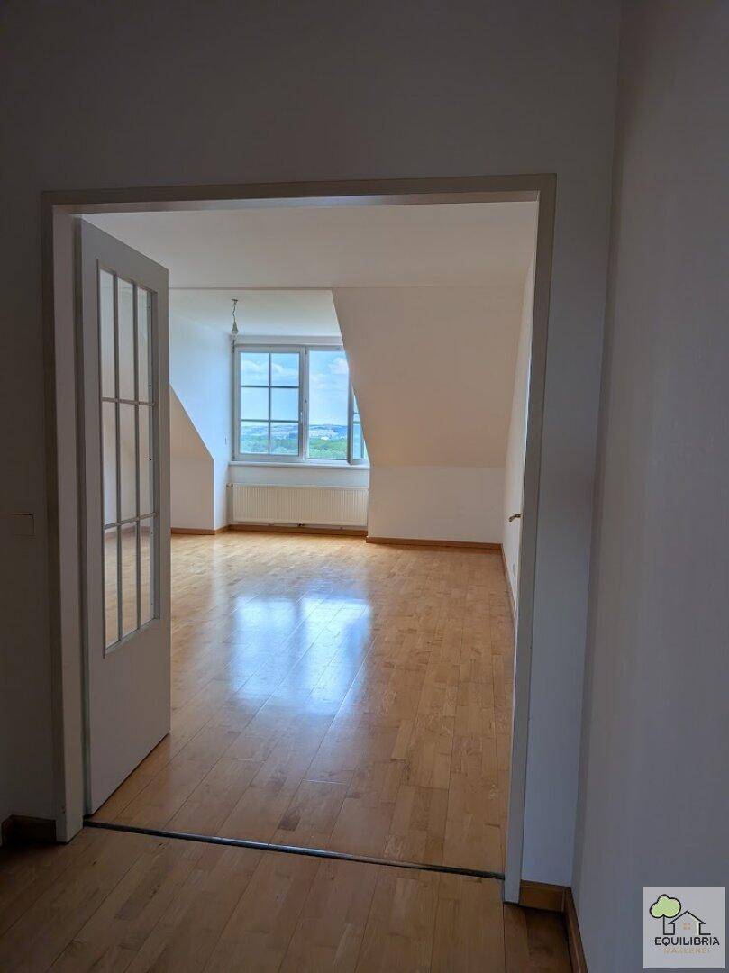 Großes, helles Zimmer im Dachgeschoss mit Holzparkett und weitem Ausblick.
