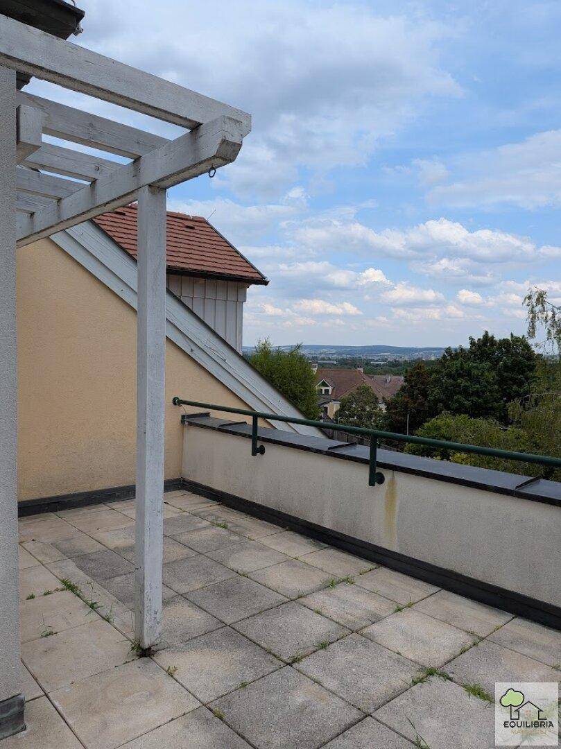 Sonniger Terrassenbereich mit weitem Blick über die Landschaft und die umliegenden Dächer.
