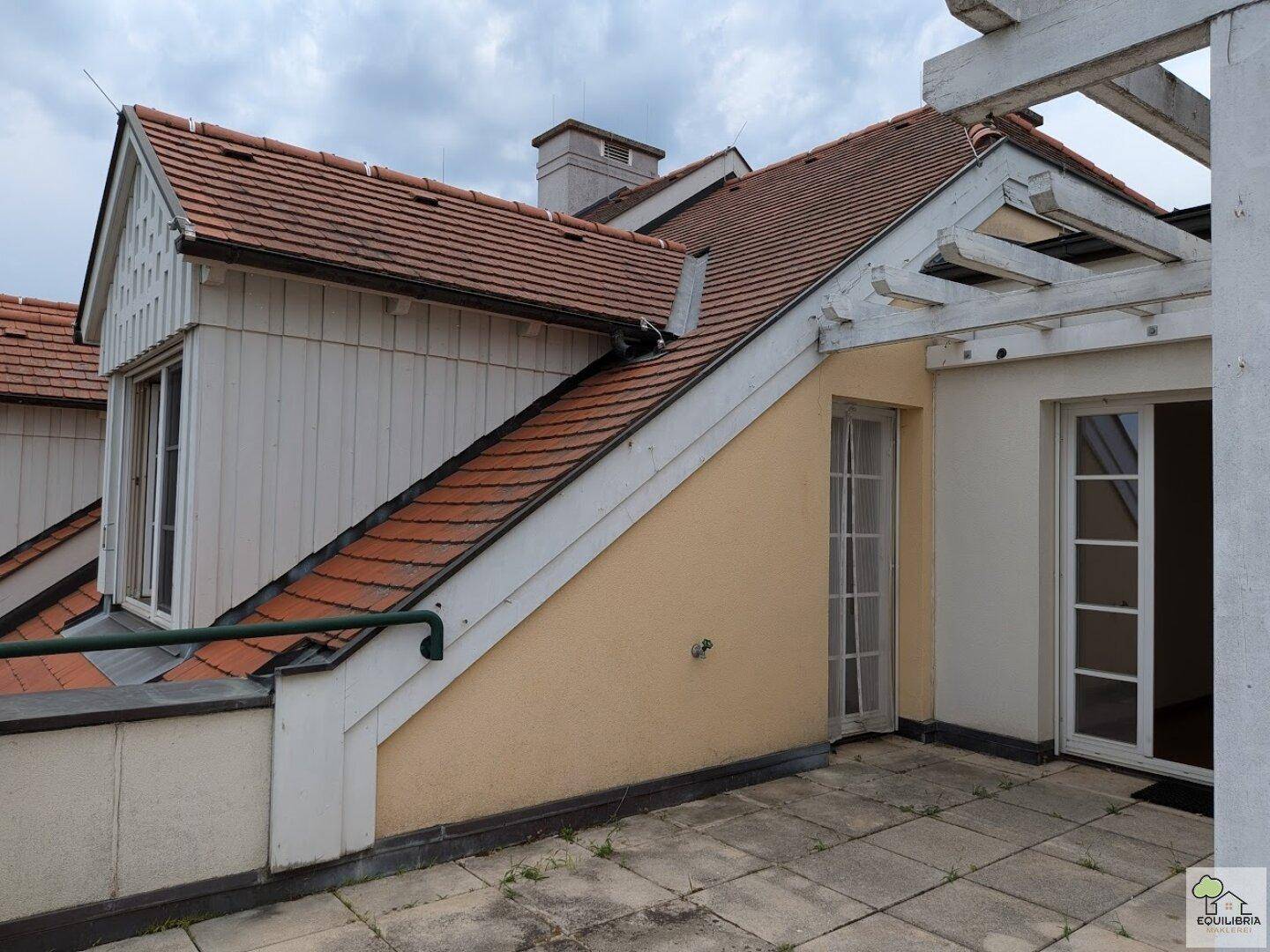Geräumige Dachterrasse mit Pergola und Zugang zu einem Zimmer, umgeben von Dachlandschaft.