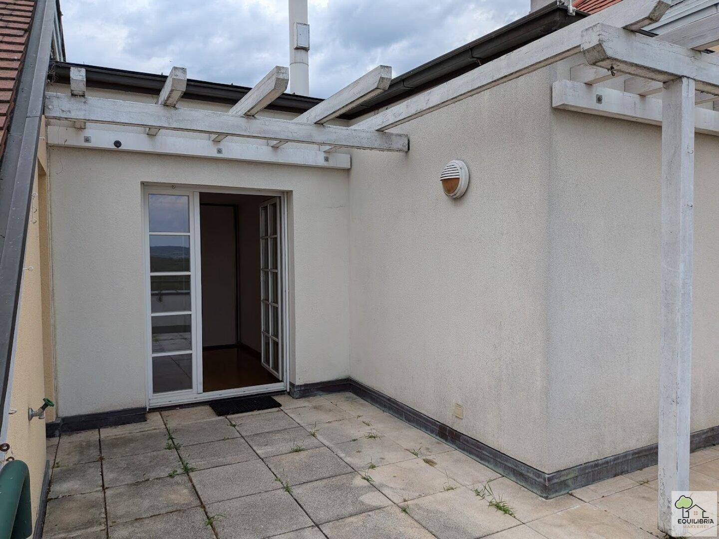 Zugang zur Dachterrasse mit einer weißen Tür und Pergola, bereit zur Gestaltung.