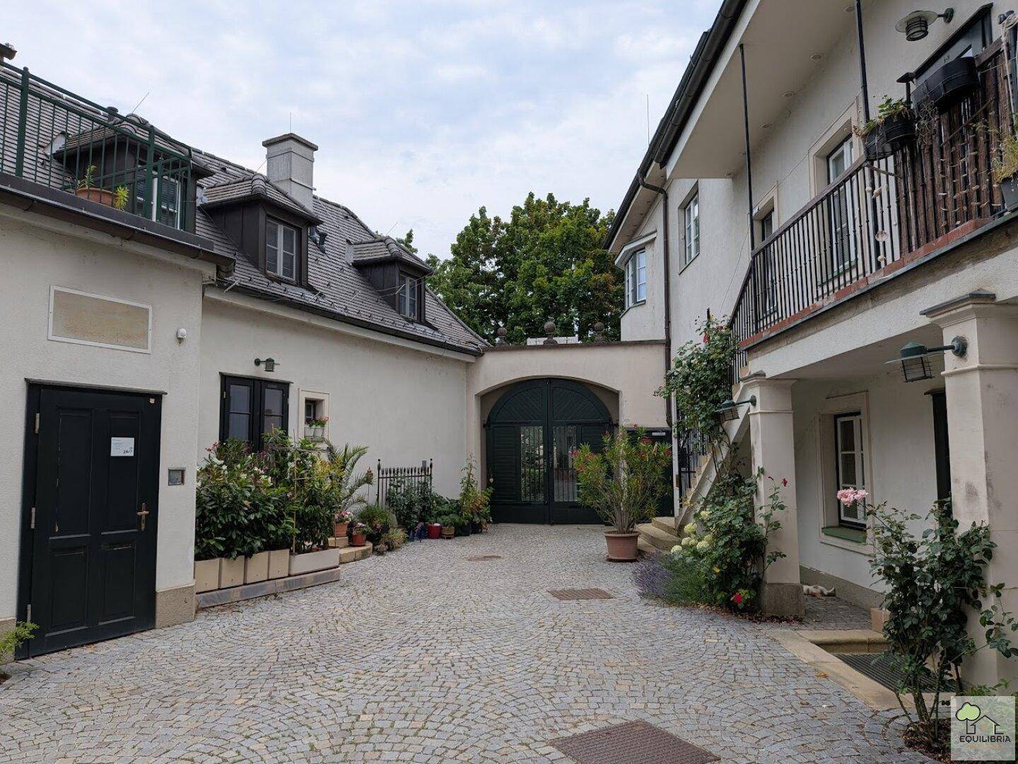 Malerischer Innenhof mit Kopfsteinpflaster und begrünten Fassaden, umgeben von Gebäuden.