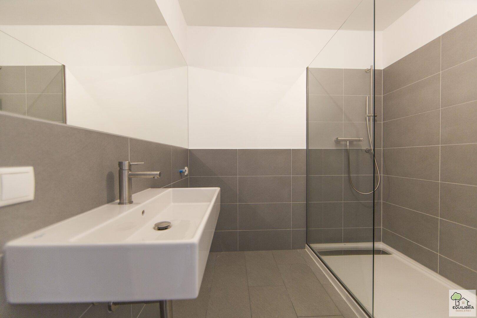 Modernes Badezimmer mit bodengleicher Dusche, Einzelwaschbecken und großem Spiegel.