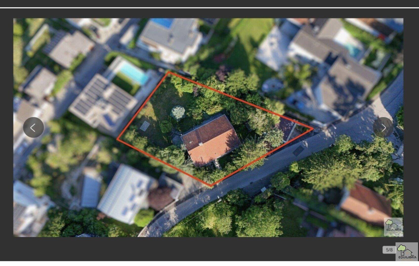 Luftaufnahme eines Grundstücks mit Einfamilienhaus und Garten, umgeben von viel Grün in einer Wohngegend.