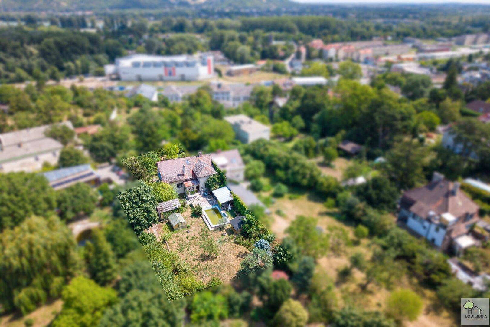 Weitläufige Luftaufnahme des Grundstücks mit Haus, Pool und der grünen Umgebung.