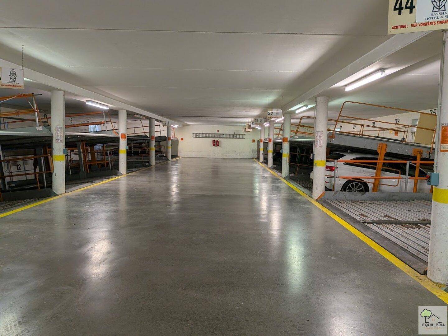 Geräumige Tiefgarage mit mehreren Parkplätzen und einem Auto.