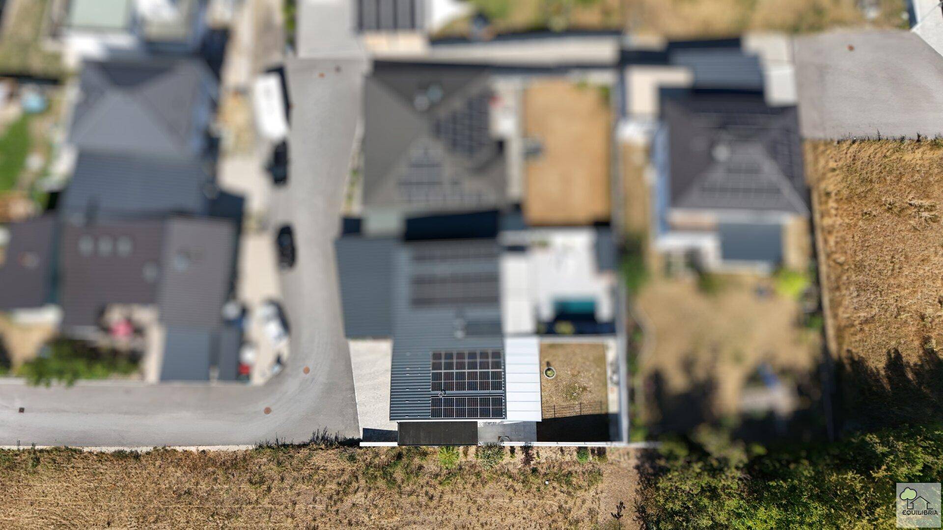 Draufsicht des Hauses mit Photovoltaikanlage und angrenzenden Grundstücken.