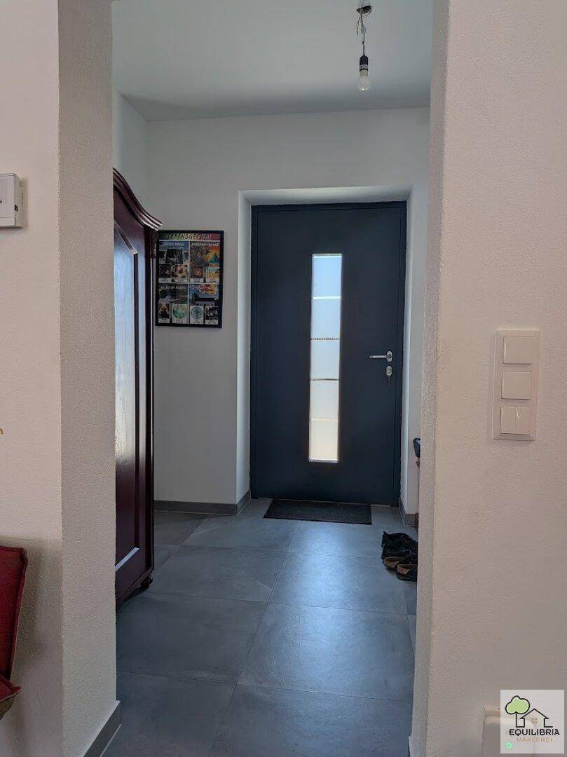 Eingangsbereich mit Fliesenboden und moderner Haustür mit Glaseinsatz.
