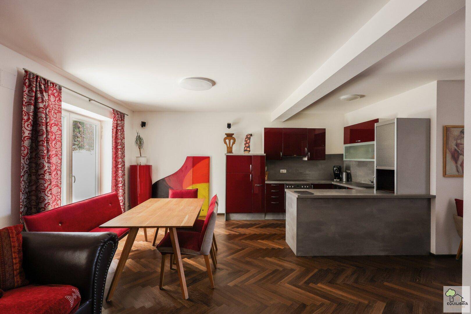 Geräumiger Wohn- und Essbereich mit offener Küche, Holzboden und Zugang zur Terrasse.