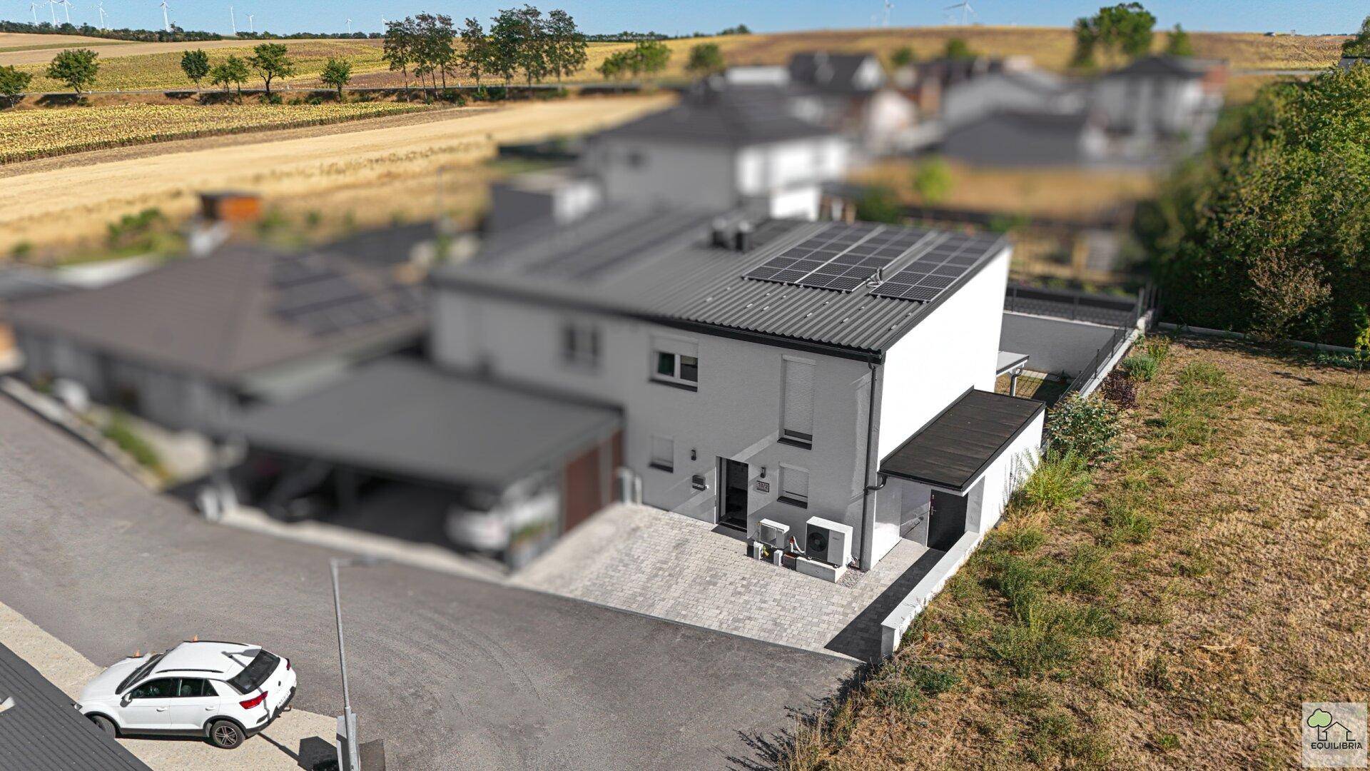 Luftaufnahme des Hauses mit Photovoltaikanlage auf dem Dach und ländlicher Umgebung.
