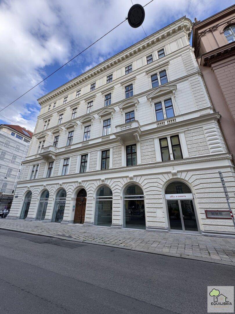 Historisches Gebäude mit klassischer Architektur, reich verzierter Fassade und kleinen Balkonen an einer städtischen Straße.