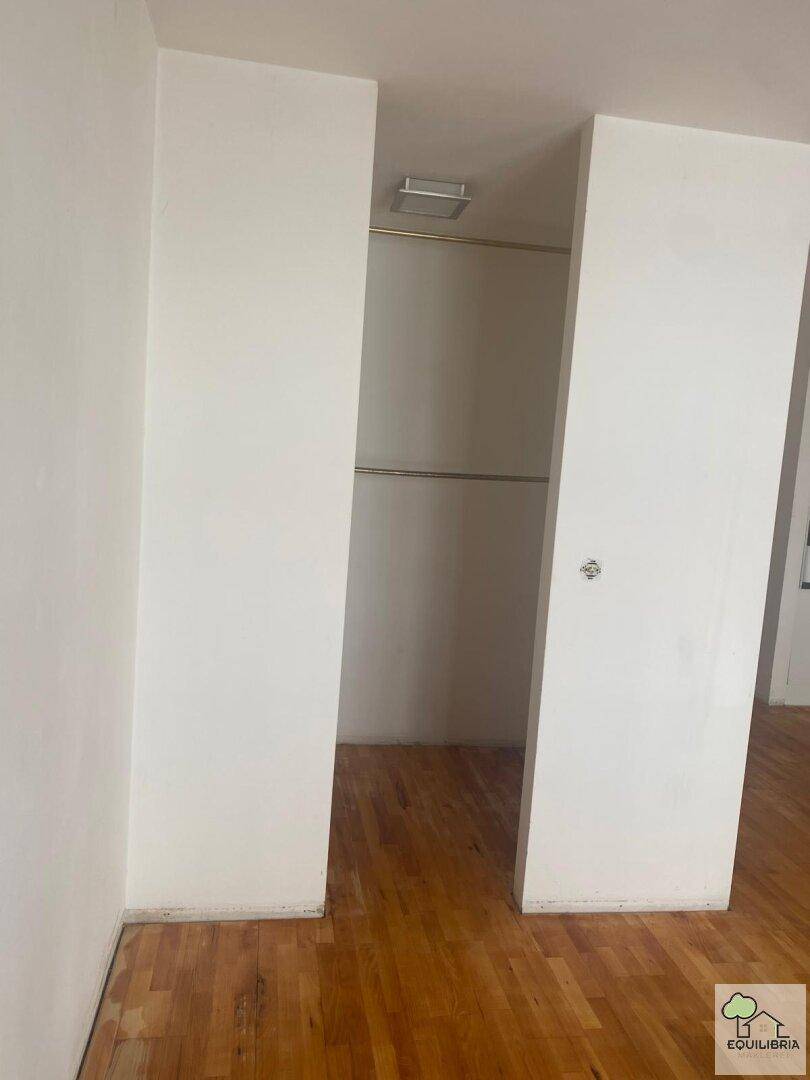 Blick in einen begehbaren Kleiderschrank mit Holzfußboden, der zusätzlichen Stauraum bietet.